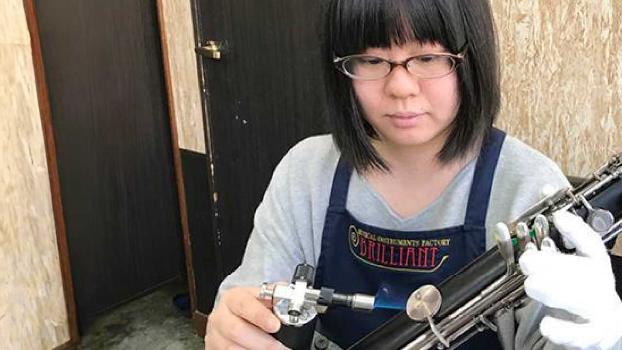 フルートを修理する楽器専門店ブリリアントの女性スタッフ